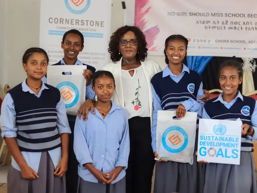 Schoolgirls with Cornerstone staff holding dignity kits